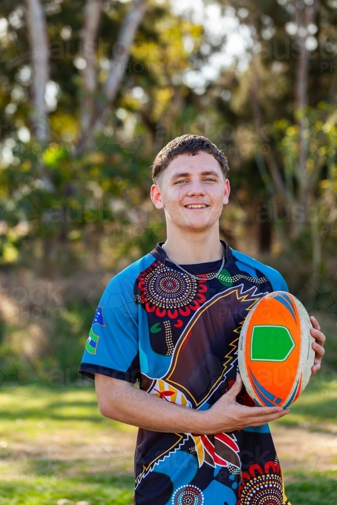 Smiling portrait of teenager holding footy ball - Australian Stock Image