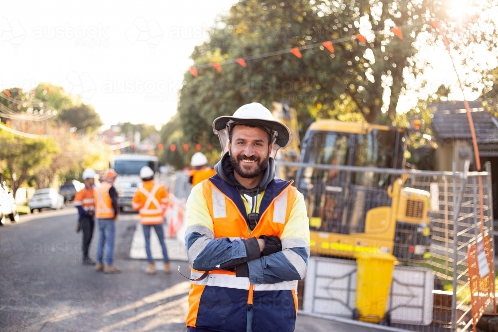 Smiling road worker man with beard wearing wearing high-vis workwear with his arms crossed - Australian Stock Image