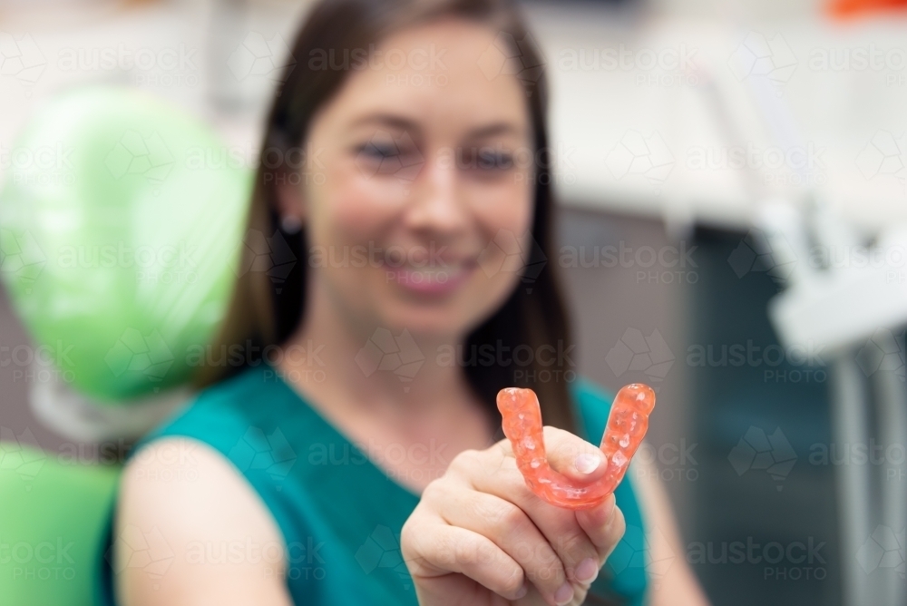 Smiling woman holding dental splint - Australian Stock Image