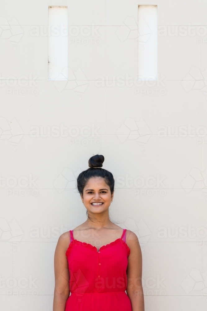 smiling woman standing against wall - Australian Stock Image