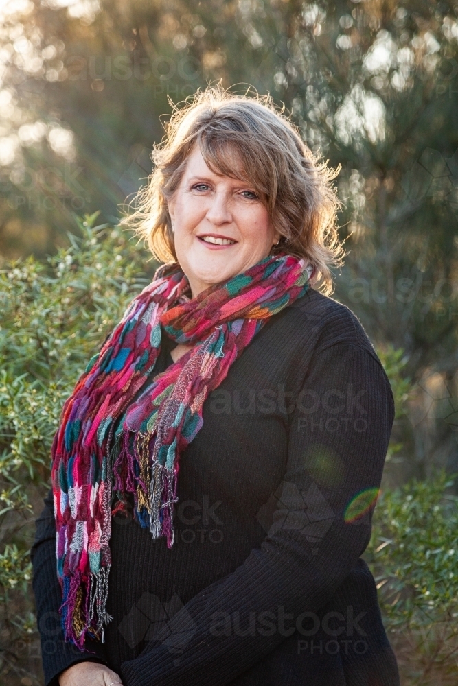 Smiling woman wearing bright scarf in winter - Australian Stock Image