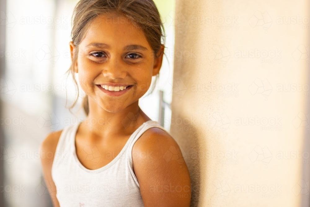 smiling young girl in white singlet looking at camera - Australian Stock Image