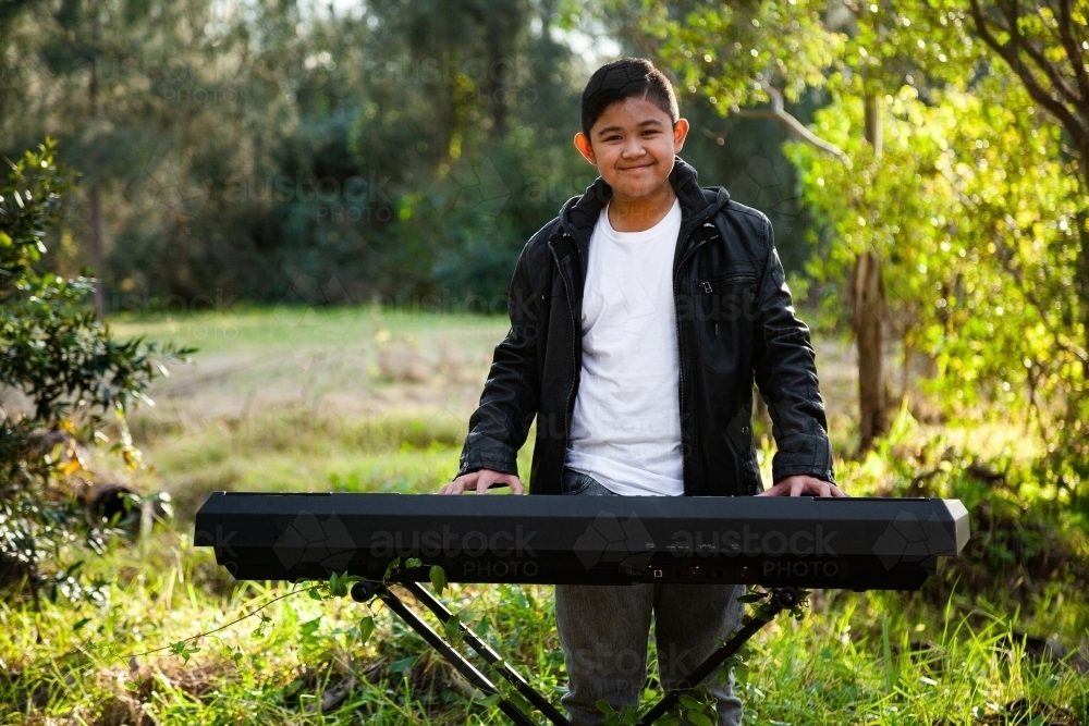 Smiling young person playing keyboard outside - Australian Stock Image