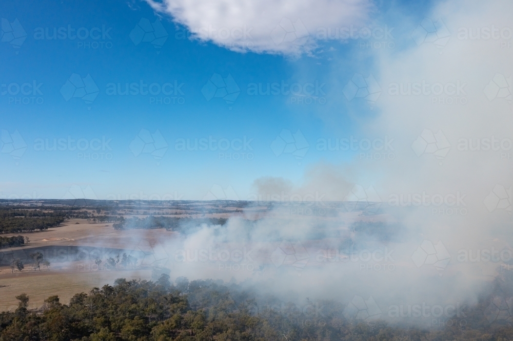 smoke rising into blue sky from rural fire - Australian Stock Image