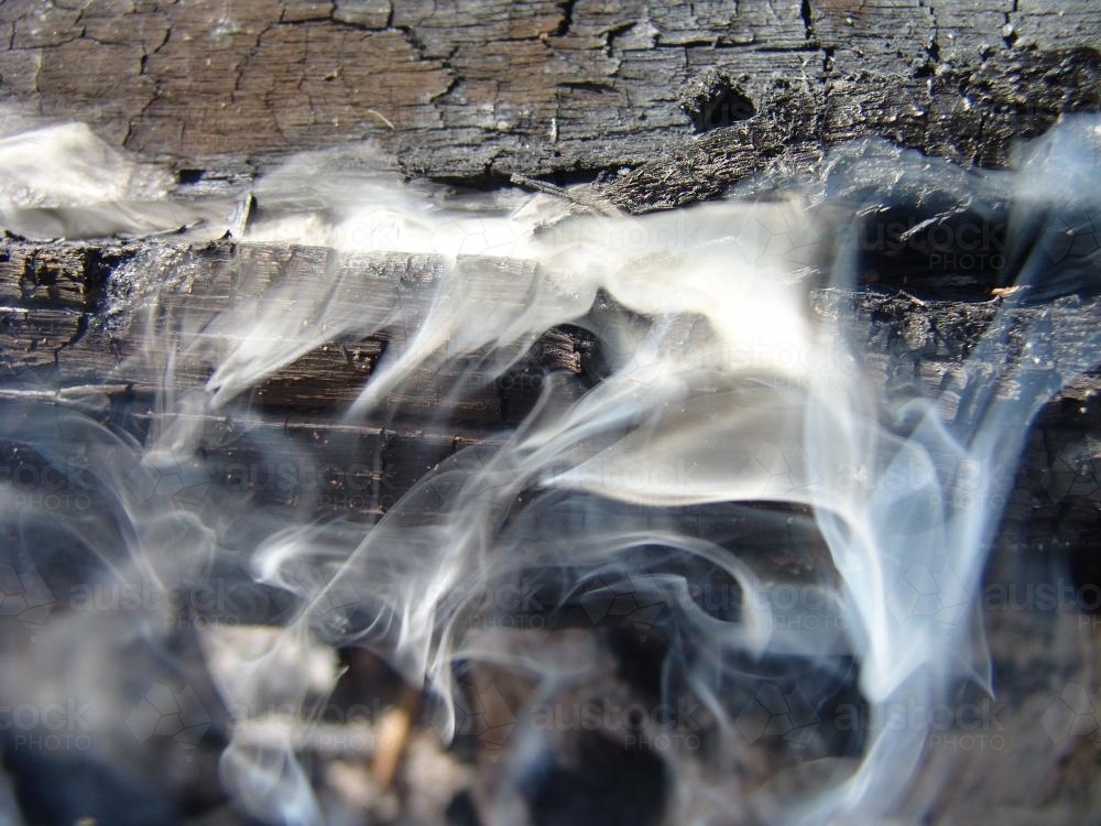 Smoke swirling out from a smouldering log - Australian Stock Image