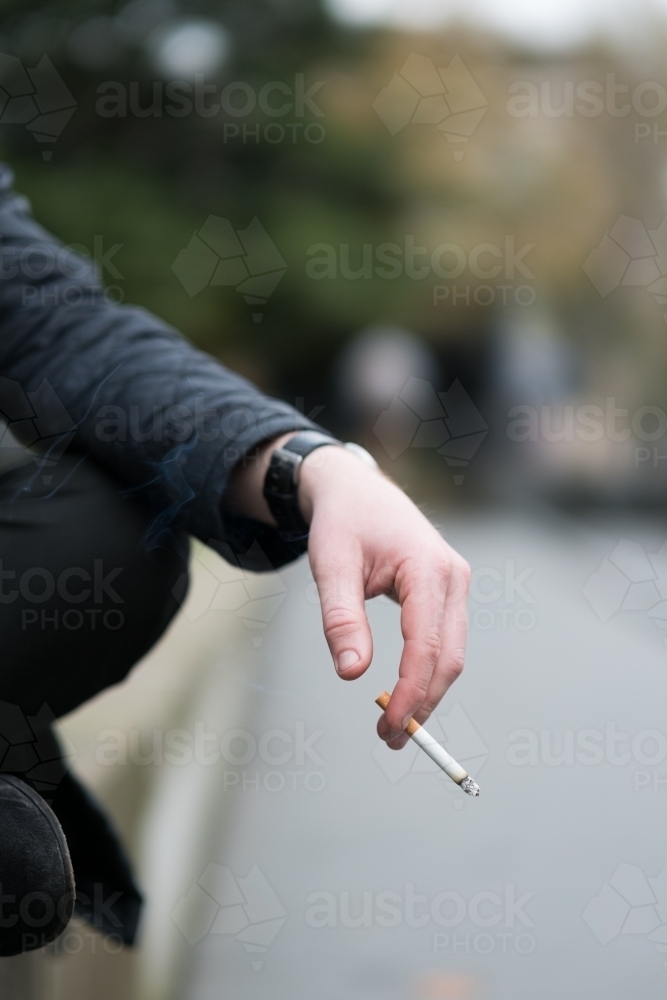 Image of Smoker holding a cigarette at outdoor smoking  