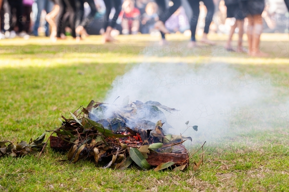 Smoking ceremony at event during aboriginal dance showing burning leaves - Australian Stock Image