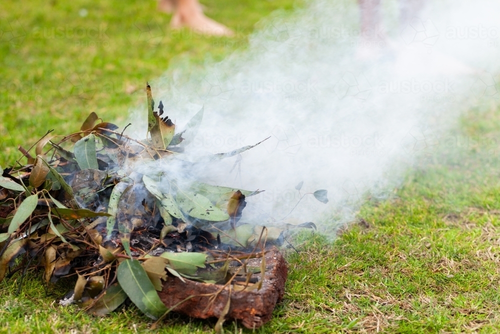 Smoking ceremony at event during dance showing burning leaves - Australian Stock Image