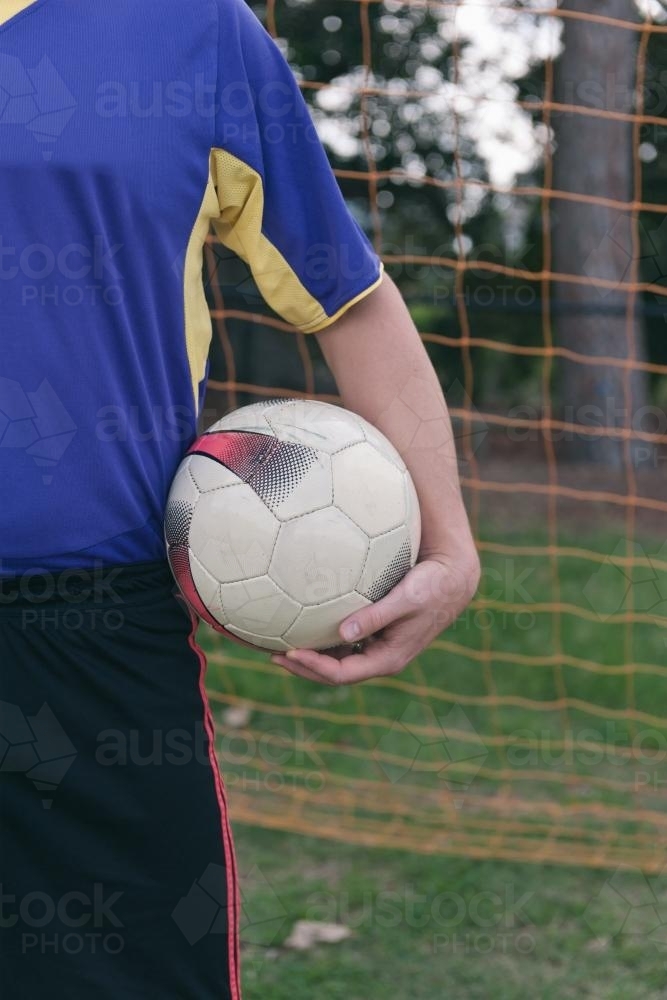 soccer ball under player's arm - Australian Stock Image