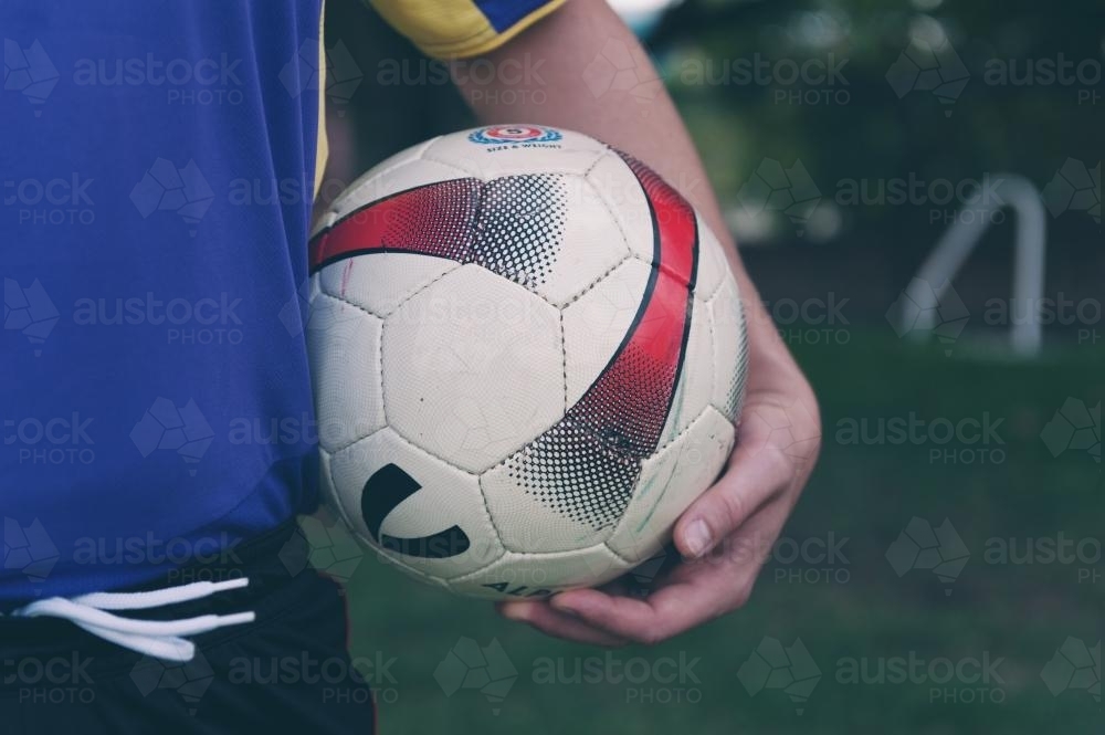 soccer ball under player's arm - Australian Stock Image