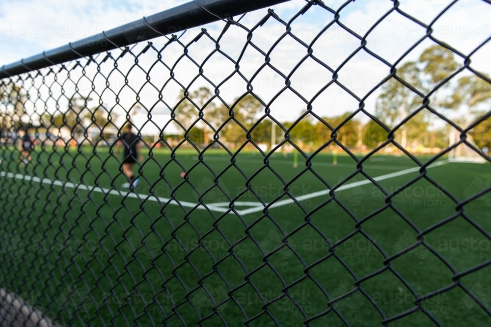 soccer training through a chain link fence - Australian Stock Image