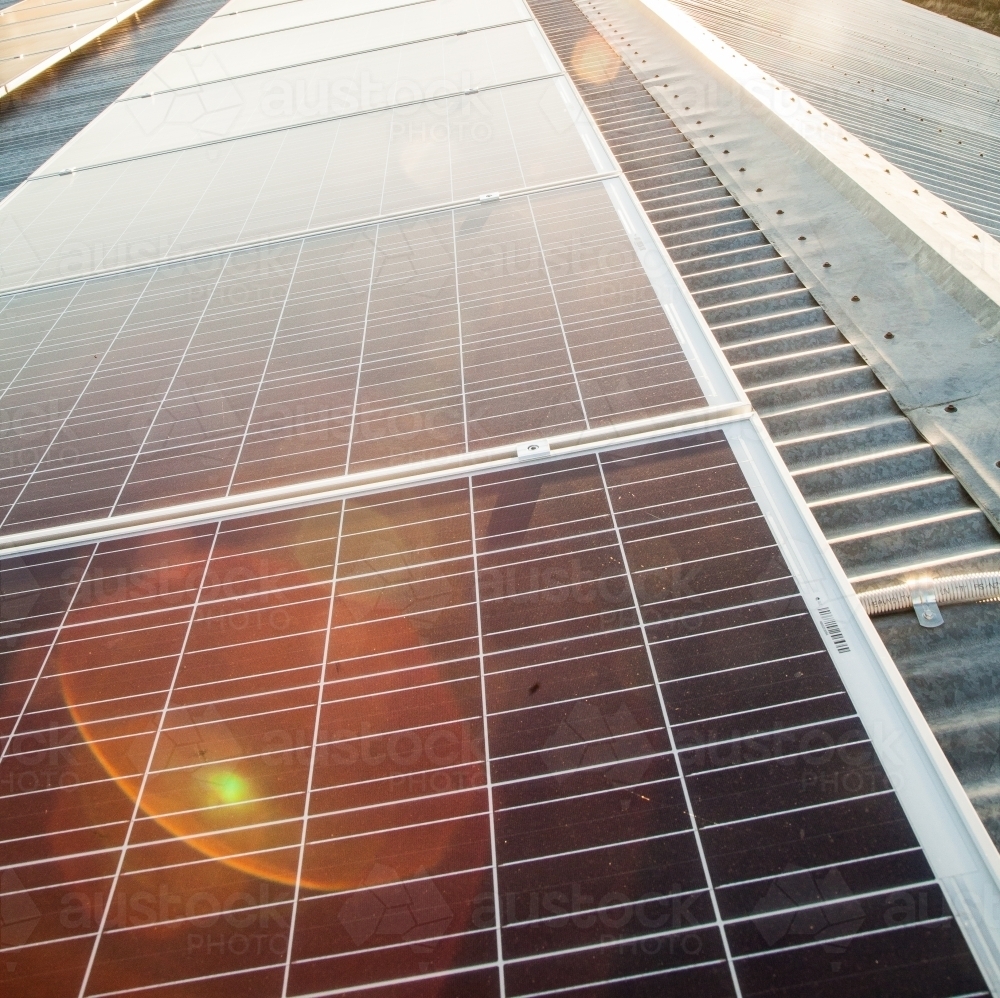 Solar panels on a shed roof generating energy with sunlight lens flare - Australian Stock Image