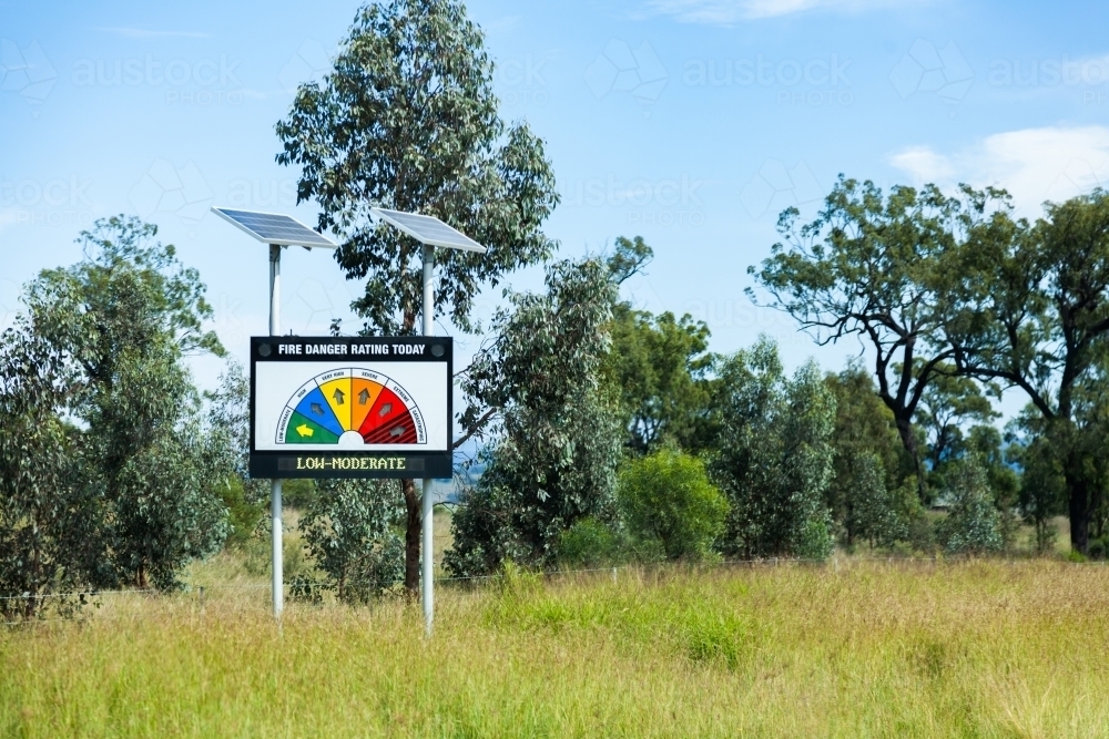 Solar panels powering a roadside fire danger rating sign alongside rural road - Australian Stock Image