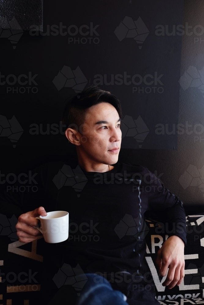 Southeast Asian multicultural man drinking coffee - Australian Stock Image