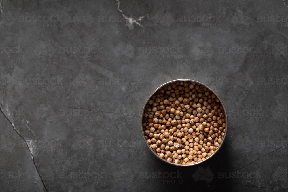 Spice tin of coriander seeds on dark marble background - Australian Stock Image