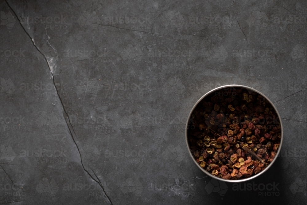 Spice tin of Sichuan pepper on dark marble background - Australian Stock Image