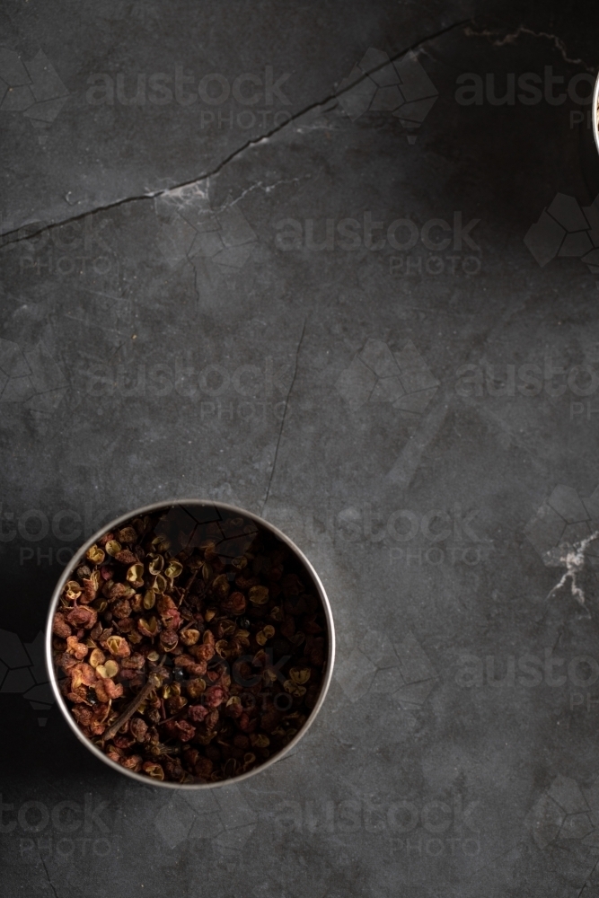 Spice tin of Sichuan pepper on dark marble background - Australian Stock Image