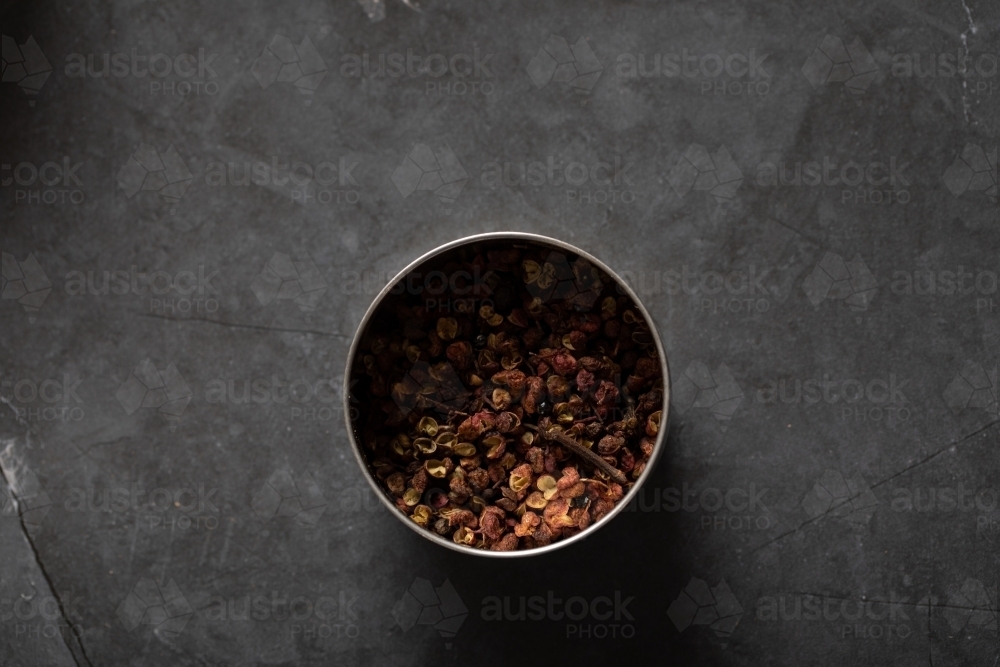 Spice tin of Sichuan pepper on dark marble background - Australian Stock Image