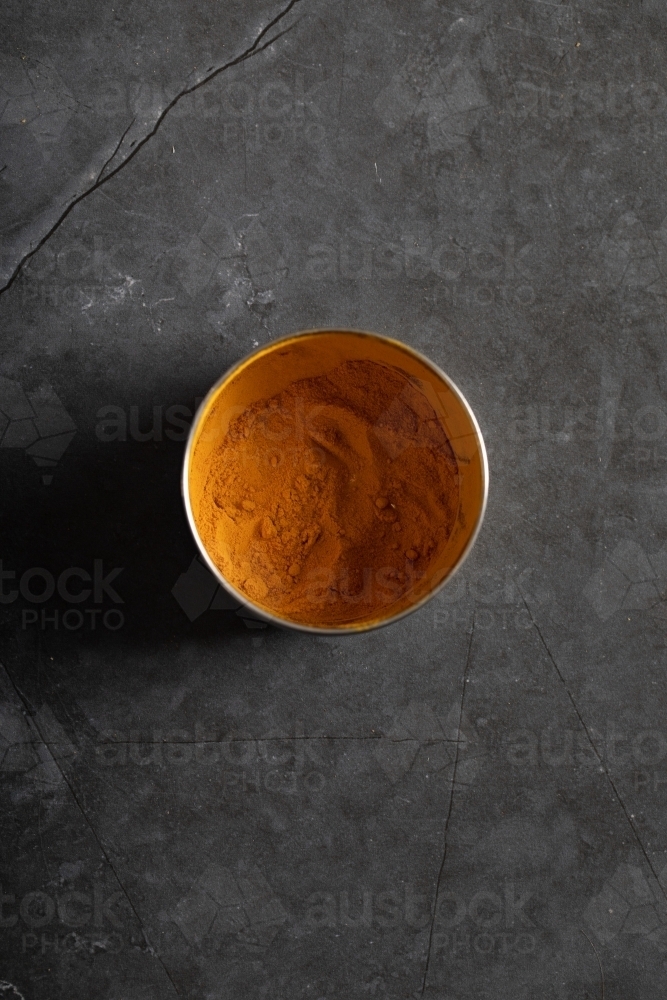 Spice tin of turmeric on dark marble table - Australian Stock Image