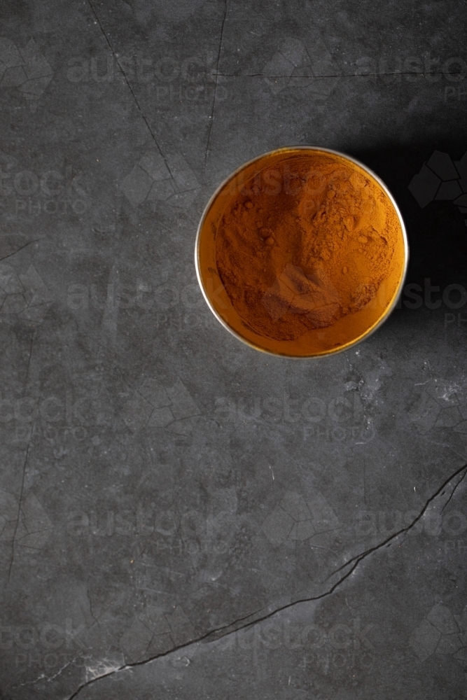 Spice tin of turmeric on dark marble table - Australian Stock Image