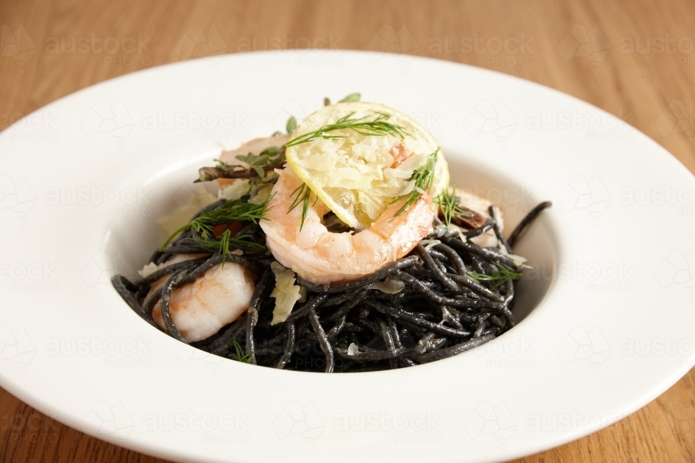Squid ink pasta with shrimp and lemon - Australian Stock Image