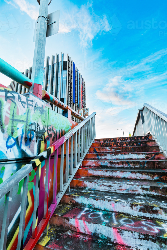 Stairs covered in graffiti leading to cloudy blue sky - Australian Stock Image