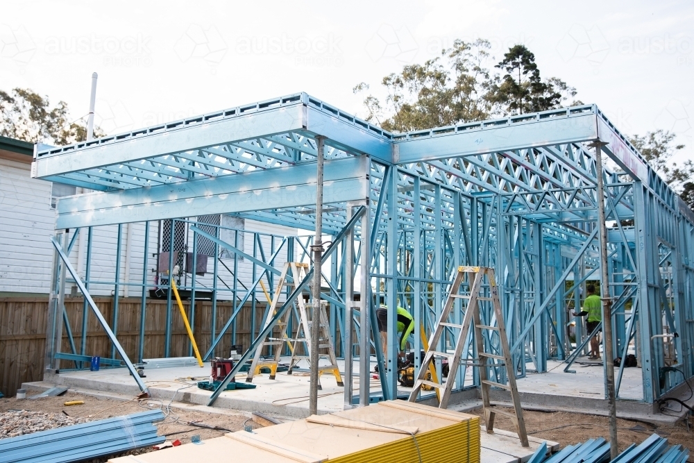 steel frame house under construction with workers building in high vis - Australian Stock Image