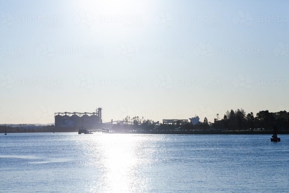 Stockton Wharf seen across blue water of Hunter river with silos behind - Australian Stock Image