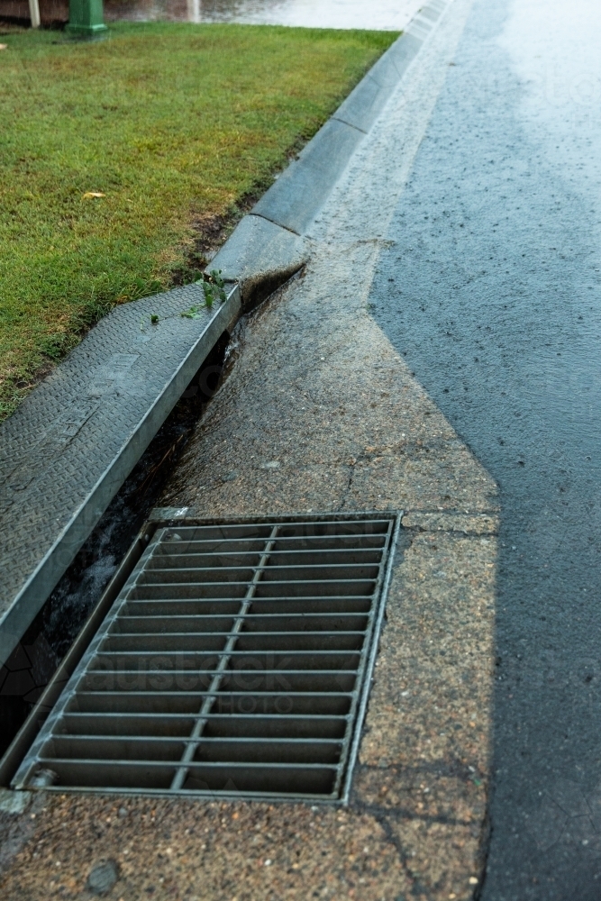 Image of storm drain and grate in the rain - Austockphoto