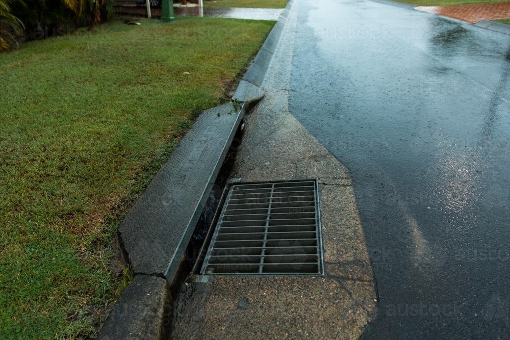 Image of stormwater drain and reflections on a wet road - Austockphoto