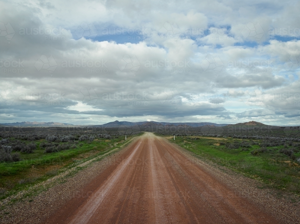 Straight gravel road leading towards a mountain range - Australian Stock Image