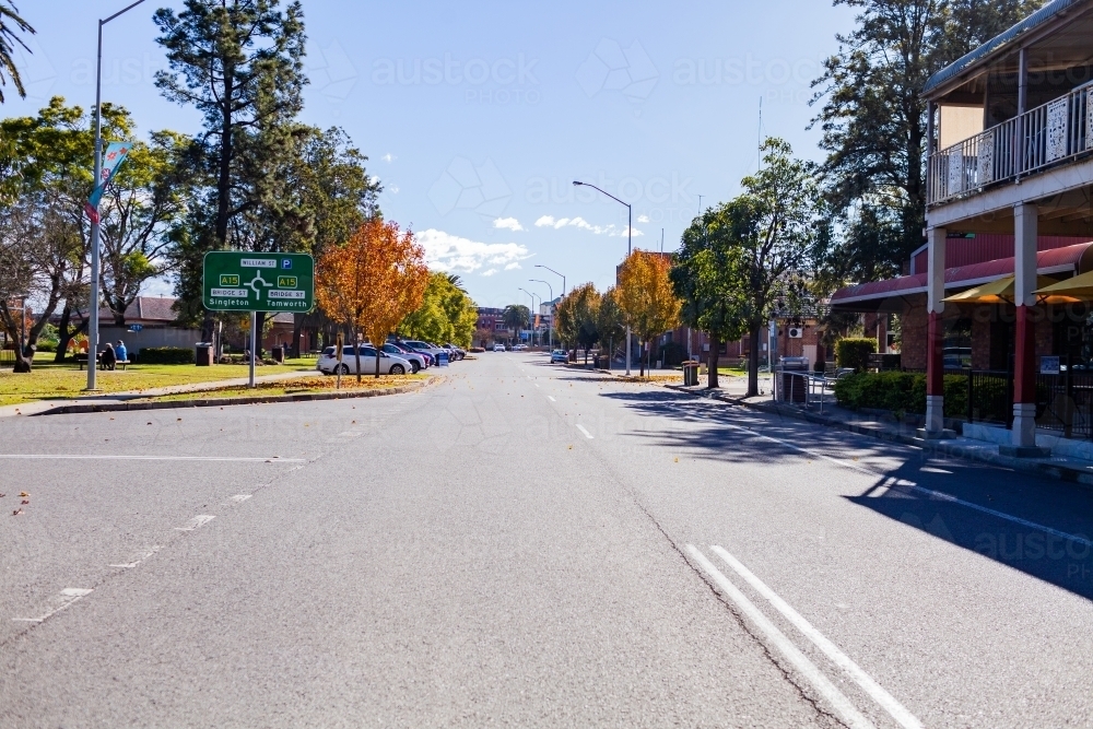 Street in Muswellbrook, NSW in autumn with cars parked beside park and sign - Australian Stock Image