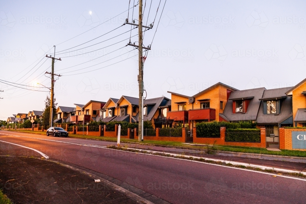 Street scene at dusk of power poles and wires and row of apartments - Australian Stock Image