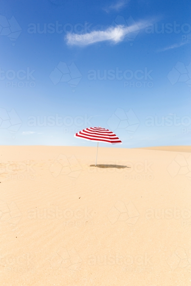 Stripy umbrella on a sand dune - Australian Stock Image