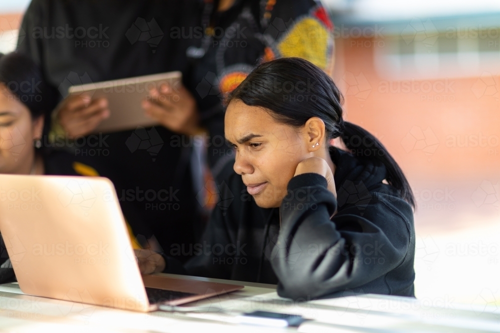 student with laptop computer sitting surrounded by other students - Australian Stock Image