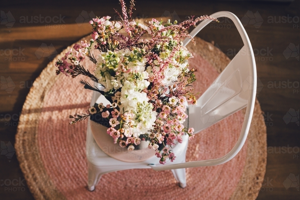 Stunning fresh flowers on a chair and pink rug from overhead - Australian Stock Image