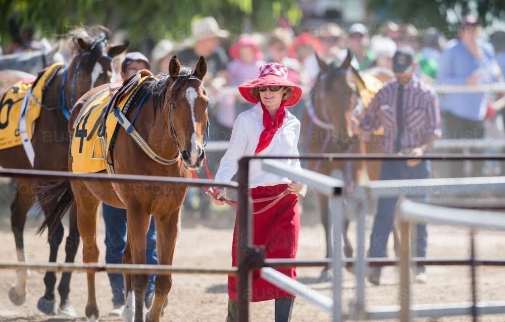 Stylish woman leads thoroughbred horse in parade ring at Outback picnic race meeting - Australian Stock Image