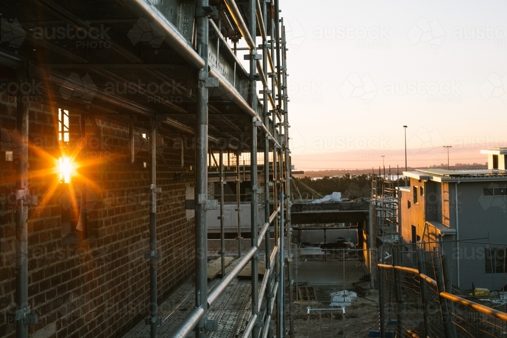 Suburban construction site with machinery and scaffolding, evening sun - Australian Stock Image