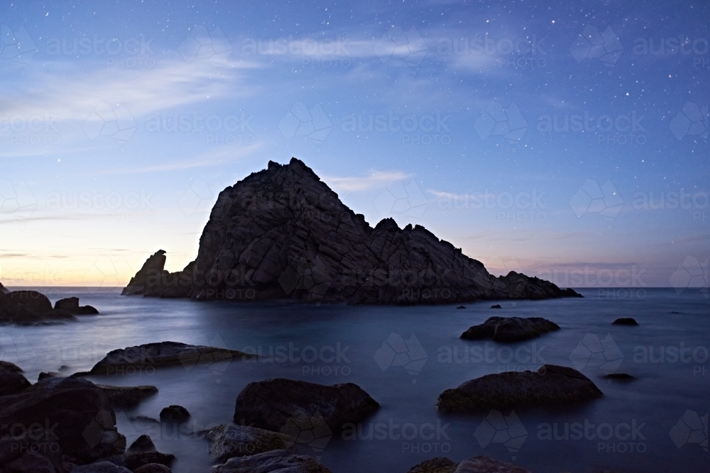 Sugarloaf Rock silhouetted against the starry dusk sky, with the last light of the day fading. - Australian Stock Image