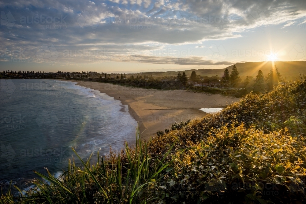 Sun setting behind empty beach - Australian Stock Image