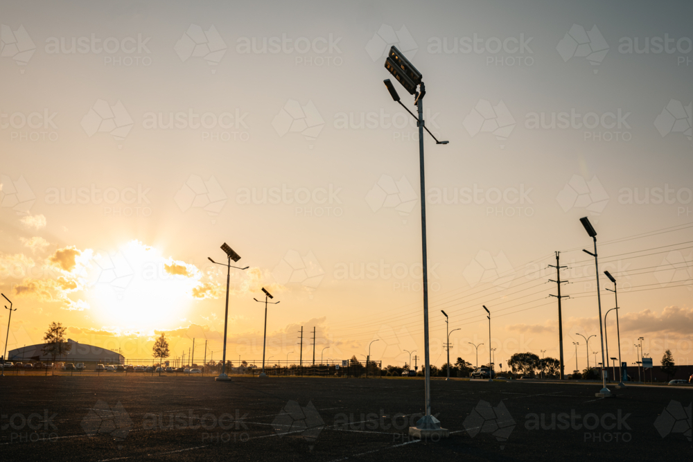 Sun setting over empty car park with solar street lights - Australian Stock Image