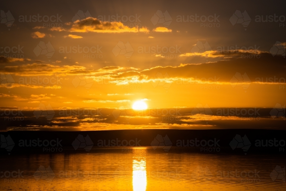 Sun setting over salt lake with reflections on the water - Australian Stock Image