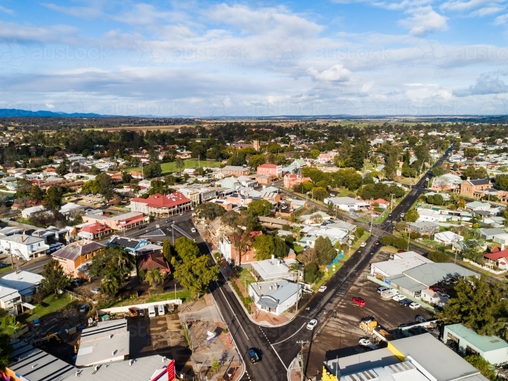 Sunlit aerial view of street corner with shops, houses and pub hotel roof painted with red flag - Australian Stock Image