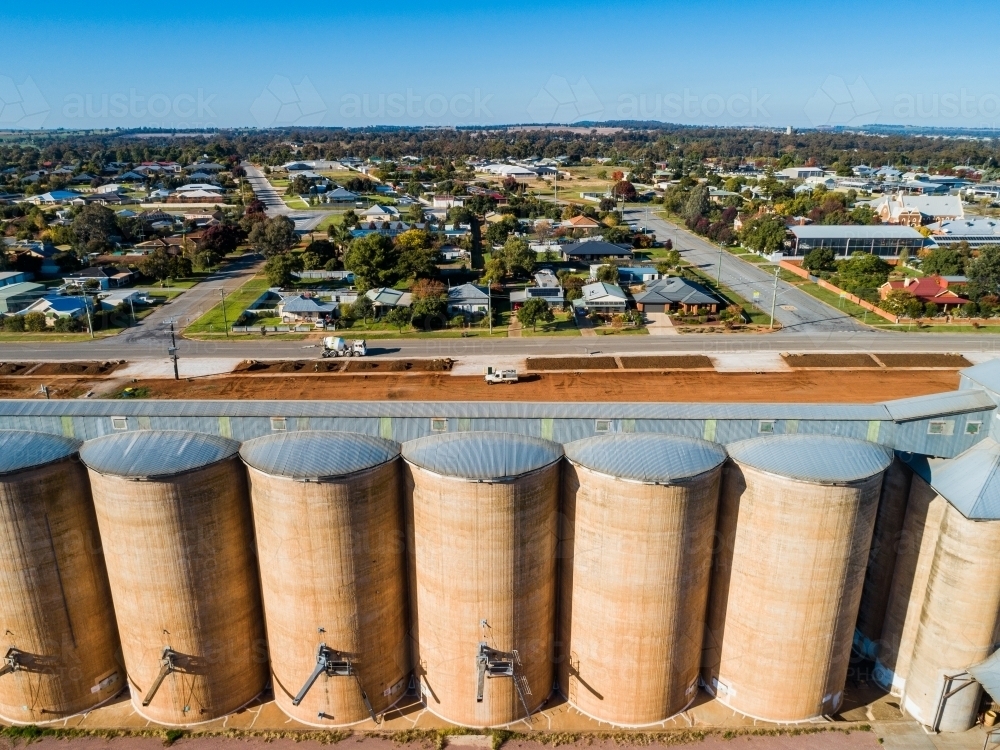 Sunlit grain silos with backdrop of rural town houses of Coolamon - Australian Stock Image