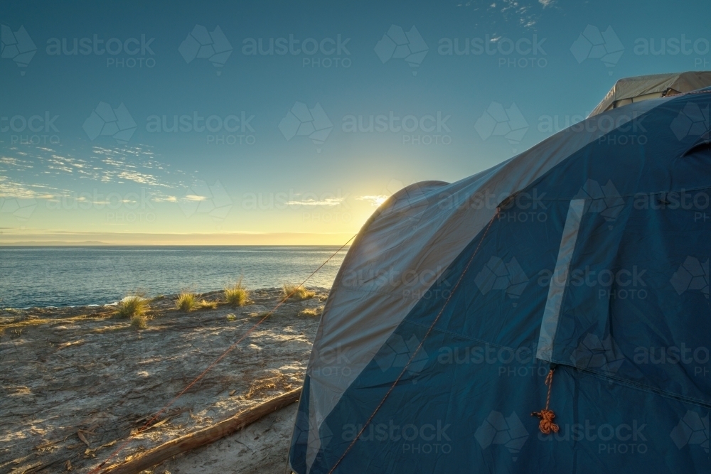 Image of sunrise at a secluded camping spot by the ocean - Austockphoto