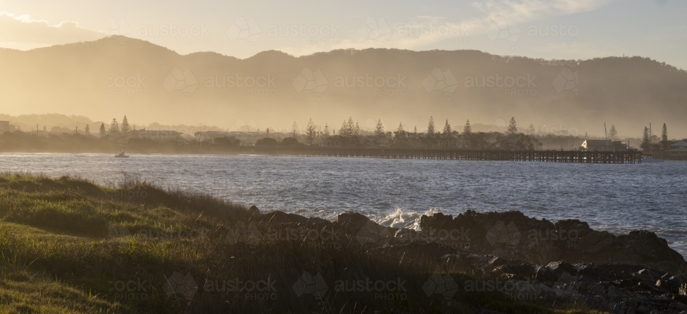 Sunrise coast view with sea mist and mountains in background - Australian Stock Image