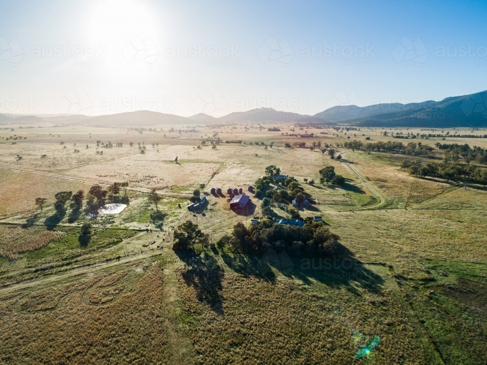 Sunrise over silvery grass on australian farm with farm house, sheds and buildings - Australian Stock Image