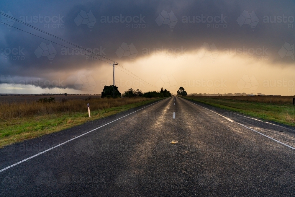 Sunset behind rain falling from a dramatic stormfront over rural farmland - Australian Stock Image