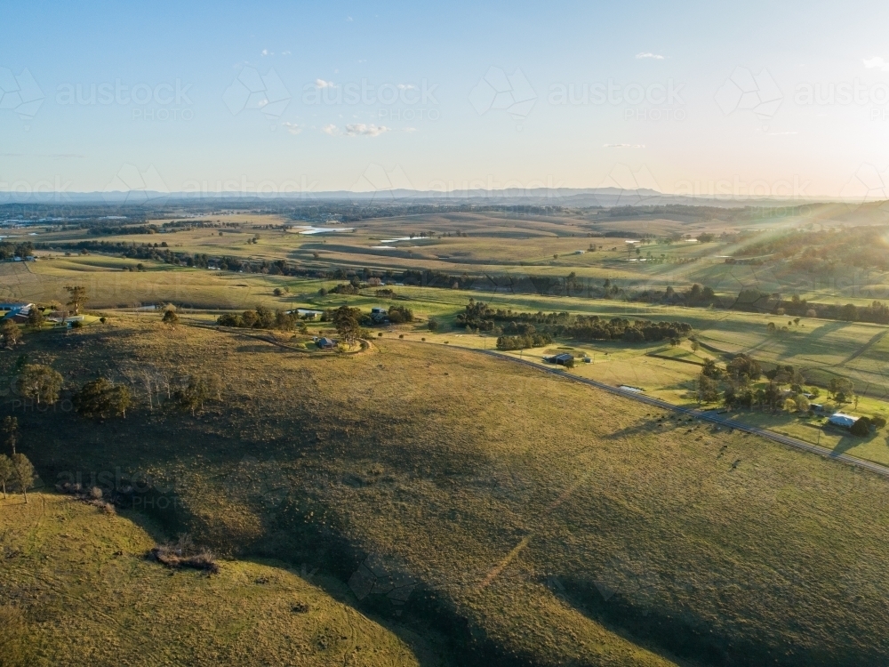 Sunset drone photo of Australian landscape with farm houses beside country road - Australian Stock Image