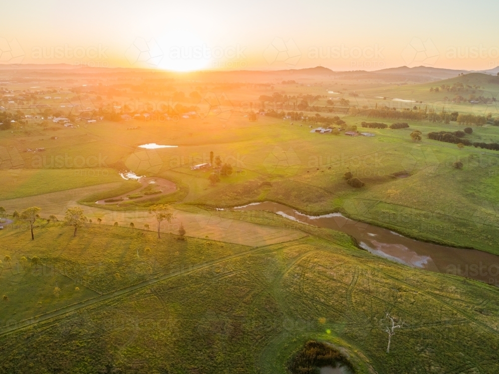 Sunset light over farmland paddock with algae weed covered creek and dam - Australian Stock Image